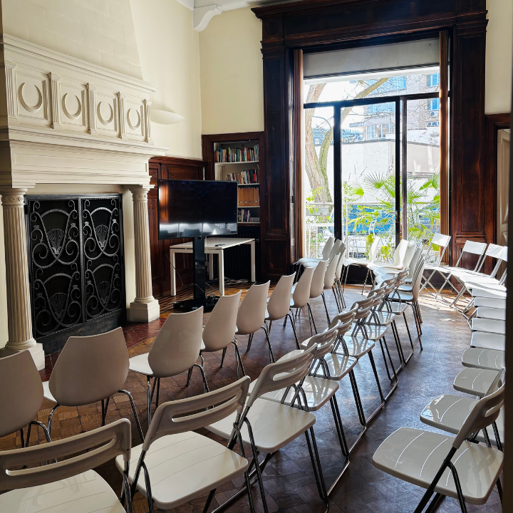 Spacious training room set up theatre-style with rows of chairs, ornate fireplace, and large windows