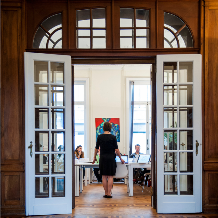Trainer addressing participants in an elegant training room viewed through open double doors at Clear Europe's office.